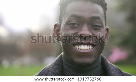 Handsome black man walks outdoors in street, smiling charismatic African person