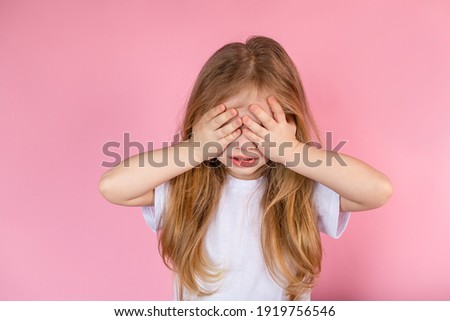 Portrait of a frustrated child who covered his eyes with his hands, closing himself from problems. Social advertising of a depressed child