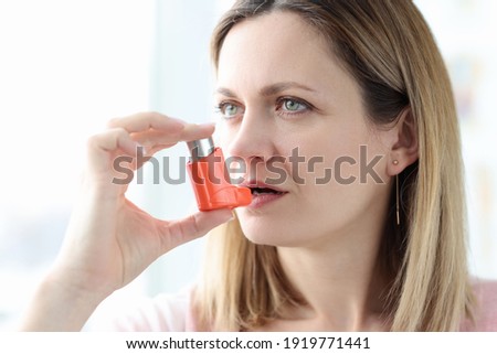 Sick woman holding hormone inhaler near mouth. Treatment of bronchial asthma concept Royalty-Free Stock Photo #1919771441