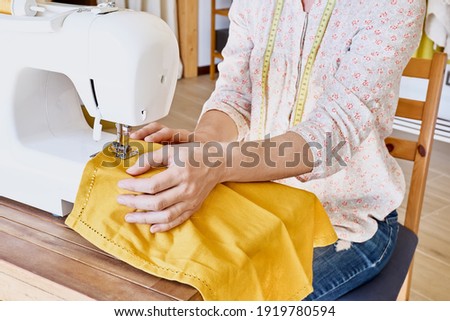 Woman sewing on sewing machine in small studio. Fashion atelier, tailor craft, handmade clothes, Industry, concept. Slow Fashion.Conscious consumption