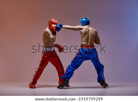 Sparring of fighting athletic males boxers wearing boxing gloves during battle, martial arts, mixed fight concept