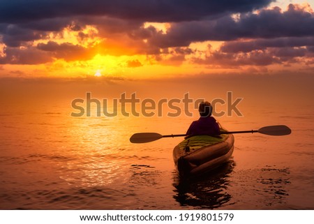 Girl kayaking on an inflatable kayak in Howe Sound. Dramatic Sunset Sky Art Render. Taken in West Vancouver, BC, Canada. Concept: Adventure, Sport, Fun Royalty-Free Stock Photo #1919801579