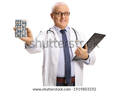 Mature doctor holding pills and a clipboard isolated on white background