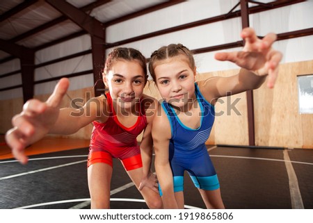 Female youth wrestling teammates in blue and red singlets