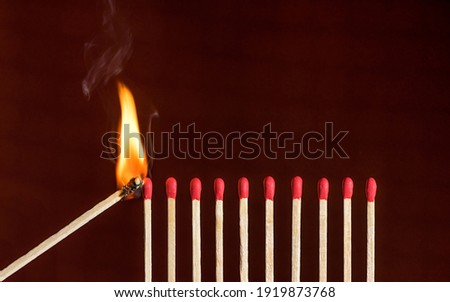  Lit match next to a row of unlit matches. Red phosphorus matches on dark red rustic background. Concept of ignition or initiation Royalty-Free Stock Photo #1919873768