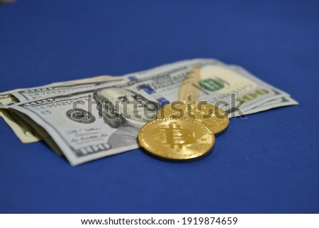 Coins Bitcoin (BTC) on background of banknotes one hundred dollars .