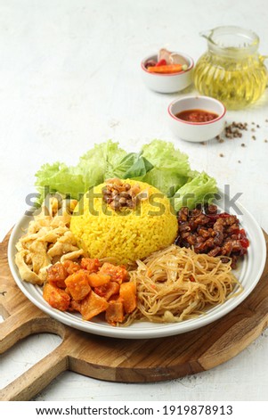Nasi kuning or Nasi kuning is a popular breakfast in Indonesia served with vermicelli, eggs and chili sauce, it tastes delicious Royalty-Free Stock Photo #1919878913