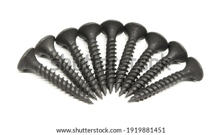 A heap of black steel screws arranged in a radial pattern