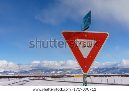 Yield Sign in Teton Valley Idaho with Sky and Snowy Winter Background