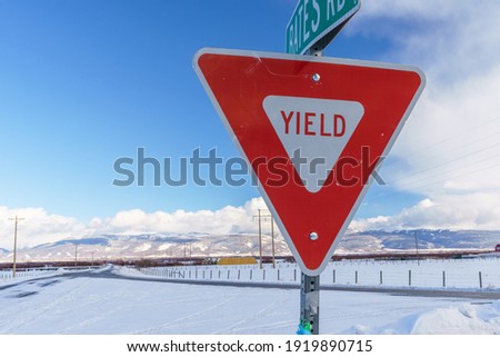 Yield Sign in Teton Valley Idaho with Sky and Snowy Winter Background