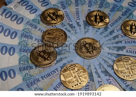 Pile of 1000 Hungarian forints, round. Multiple gold bitcoin digital cryptocurrency coins scattered. Bank image and photo background.