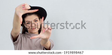 Creative good-looking woman using imagination picturing new appartment design how capture you making finger frame looking through, smiling white background