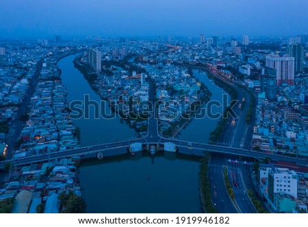 Aerial view of symmetrical traffic bridge at night across a canal in urban area.