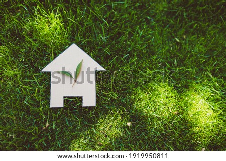 green home and eco-friendly construction conceptual image, house icon on green grass lawn under the sun with two leaves on top Royalty-Free Stock Photo #1919950811