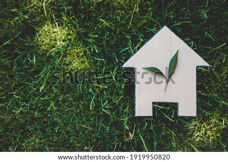 green home and eco-friendly construction conceptual image, house icon on green grass lawn under the sun with two leaves on top Royalty-Free Stock Photo #1919950820