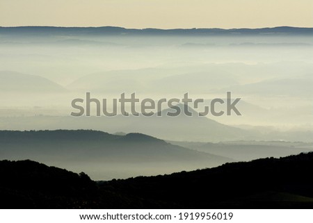 An aerial shot of muntains in layers under a foggy sky Royalty-Free Stock Photo #1919956019