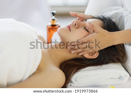 Adult beautiful asian women black long hair sleep for head massage spa service with covered wrap by white towel on her look feel relax and blurry with flowers background.