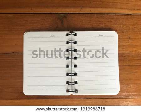Top view blank notebook on wood table background in office workplace.