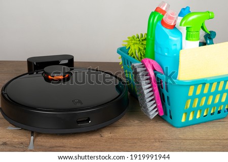 Picture of an automatic intelligent robotic vacuum cleaner  and  colorful cleaning product on the floor