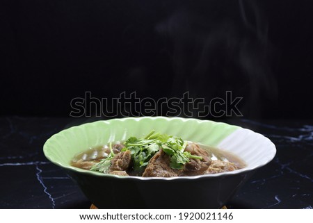 Classic gravy soup of pork rib topping with fresh coriander serving in the bowl. Famous hot soup menu in Asia restaurant. 