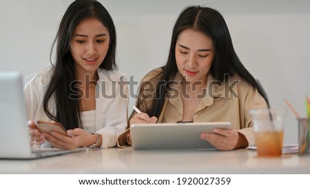 Portraits of group of businesswomen discussing on their project and using digital tablet and smartphone