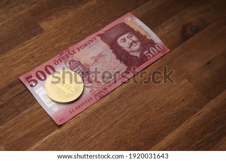 500 HUF banknote Portrait of II. Ferenc Rákóczi. Brown wooden table. Next to it is a gold bitcoin digital cryptocurrency coin. Bank image and photo.