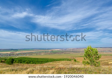 Autumn landscape photography, the European part of the Earth. Rural landscape with a beautiful gradient of the evening sky at sunset. Green field and village on the horizon