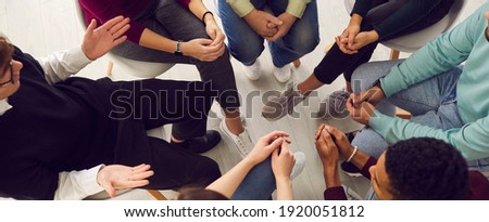 Top view of diverse people sitting in a close circle and talking to a therapist. Cropped image of unidentified people receive help and support during a group therapy session. Concept of group therapy. Royalty-Free Stock Photo #1920051812