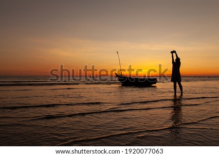 Female photographer raised the camera to take a picture in twilight time at the beach in phangnga, Thailand