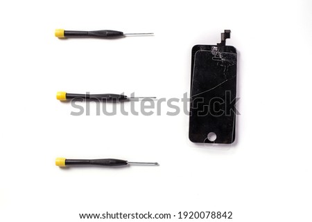 Three screw drivers and a cracked phone screen, isolated on white background