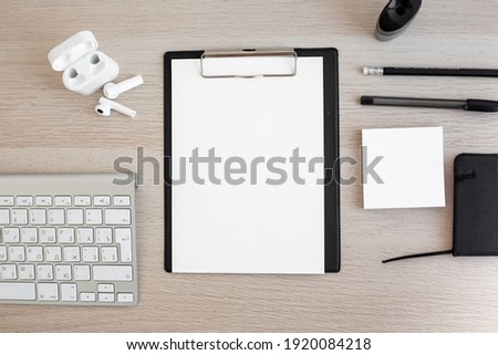Horizontal photo of the workplace. White paper for writing, keyboard, pens on a wooden desktop. Design in the style of minimalism