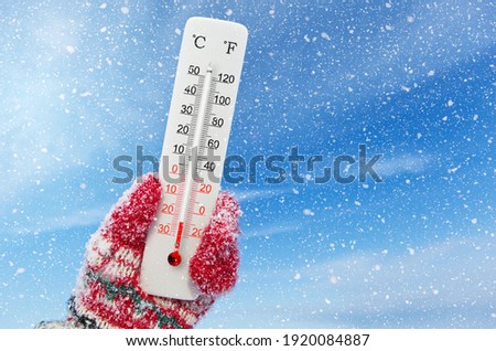 White celsius and fahrenheit scale thermometer in hand. Ambient temperature minus 23 degrees celsius Royalty-Free Stock Photo #1920084887