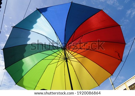 A bright rainbow colored umbrella in the afternoon. Symbol of different  yet beautiful thing in harmony.