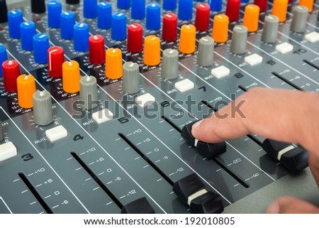 Hand making slide on an audio soundboard