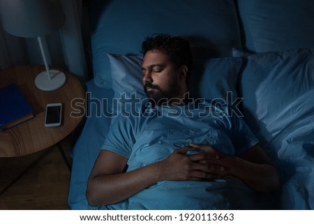 people, bedtime and rest concept - indian man sleeping in bed at home at night Royalty-Free Stock Photo #1920113663