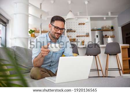 Man  rest on sofa put notebook on lap looking at screen watching movie enjoy lazy free day, creates blog, booking on-line, buyer choose goods makes order, shopping in internet lifestyle concept Royalty-Free Stock Photo #1920136565