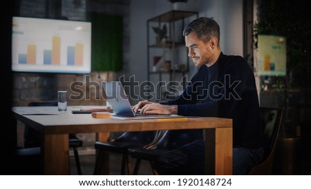Handsome Caucasian Male is Working on Laptop Computer while Sitting Behind a Conference Table in Meeting Room in an Creative Agency. Project Manager is Busy With Business Strategy and Development. Royalty-Free Stock Photo #1920148724