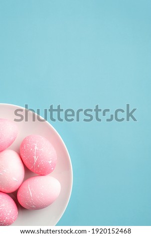 Happy Easter minimal concept. Pink Easter eggs in plate on turquoise background. Flat lay, top view, copy space.