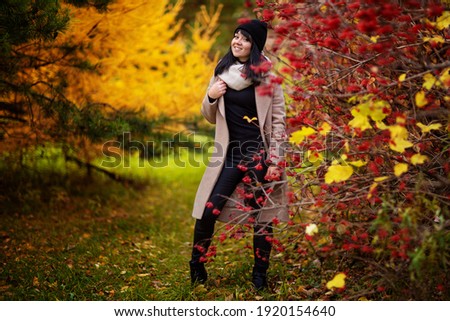 stylish and cheerful brunette in an autumn park