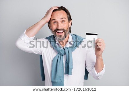Photo of impressed age man wear white shirt sweater shoulders holding credit card arm head isolated grey color background