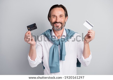 Photo portrait of smiling businessman in white shirt showing plastic bank credit cards isolated pastel grey color background