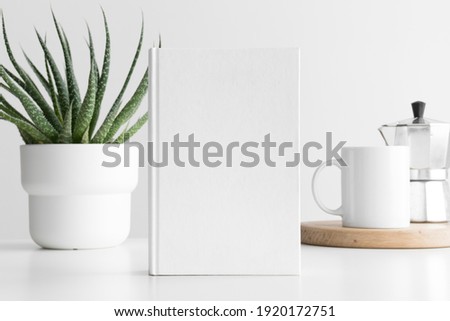 White book mockup with a succulent plant and a mug on a white table. Royalty-Free Stock Photo #1920172751