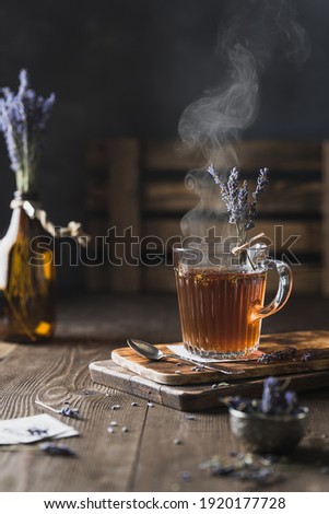 A  cup of lavender tea with steaming. Still lifestyle photo. Wooden background. Lavender bouquet.