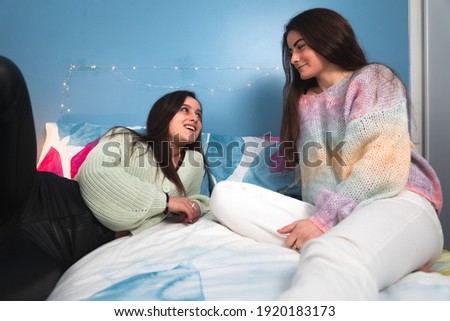 Two cute young women laying on a bed