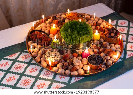 Novruz traditional tray with green wheat grass semeni or sabzi, sweets and dry fruits and festive candles with tea. Traditional celebration of spring equinox in March in Azerbaijan 
