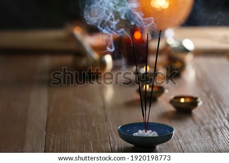 Incense sticks smoldering on wooden table in room. Space for text Royalty-Free Stock Photo #1920198773