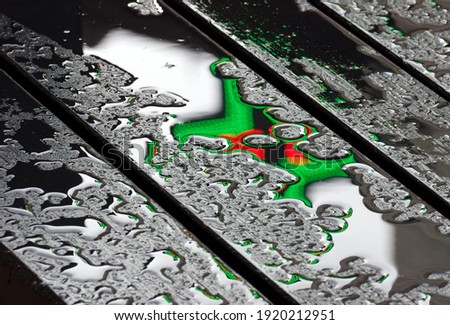 Reflection of a neon sign on a wet park bench