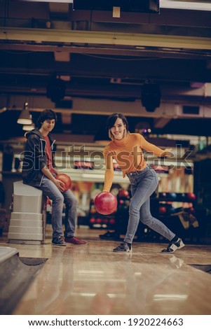 Couple in bowling alley. Smiling Woman throws a bowling ball.