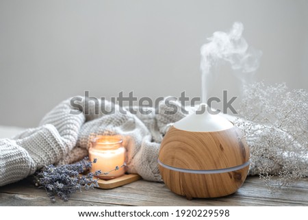 Aroma composition with a modern aroma oil diffuser on a wooden surface with a knitted element, candle and lavender. Royalty-Free Stock Photo #1920229598