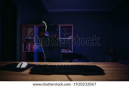 Gaming place in the room with armchair and keyboard and mouse on the table against the background of the bedroom.